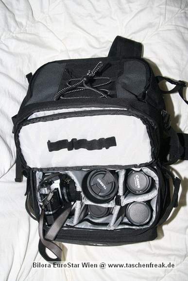 Foto von Bernd Binnewies - DANKE DAFR!\n\nKommentar des Nutzers:\n\nEs handelt sich um einen kombinierten Rucksack. Er hat zwei Fcher. Im oberen Fach knnen alle Utensilien mitgenommen werden, die man fr einen Ausflug bentigt. Im unteren Teil befindet eine herausnehmbare Tasche fr die Kameraausrstung. Die Tasche knnte auch separat benutzt werden. Aufgrund ihrer Beschaffenheit, ist dies aber nur z.B. in der Wohnung/ Gebuden ratsam. Die Fcher der Tasche lassen sich mit den blichen Trennwnden per Klett verstellen. Bei mir reicht der Platz fr eine Canon EOS 350D, an dem sich standardmig ein Tamron 28-75 2,8XR Di befindet. Weiterhin sind in dem Rucksack noch 4 Objektive Canon EF 50/1,8; Canon EF 100/2,0; Canon EF-S 18-55, Tamron 70-300) ein Blitz und der erforderliche Kleinkram (Speicherkarten, Filter). Der Kleinkram befindet sich in einer aufgesetzten Frontasche, die am unteren Teil des Rucksacks angebracht ist. \n\nDer Rucksack hat einen Brustgurt, einen Bauchgurt und ausreichend breite Schultergurte. Auerdem hat er eine integrierte Regenhlle. Die Rckenbelftung knnte sicher besser sein, aber dieses Manko macht der relativ gnstige Preis wieder wett.