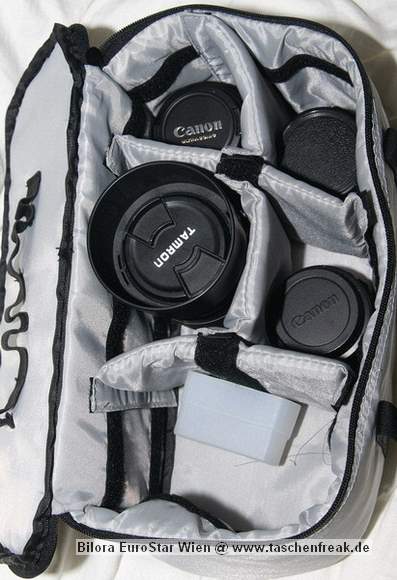 Foto von Bernd Binnewies - DANKE DAFR!\n\nKommentar des Nutzers:\n\nEs handelt sich um einen kombinierten Rucksack. Er hat zwei Fcher. Im oberen Fach knnen alle Utensilien mitgenommen werden, die man fr einen Ausflug bentigt. Im unteren Teil befindet eine herausnehmbare Tasche fr die Kameraausrstung. Die Tasche knnte auch separat benutzt werden. Aufgrund ihrer Beschaffenheit, ist dies aber nur z.B. in der Wohnung/ Gebuden ratsam. Die Fcher der Tasche lassen sich mit den blichen Trennwnden per Klett verstellen. Bei mir reicht der Platz fr eine Canon EOS 350D, an dem sich standardmig ein Tamron 28-75 2,8XR Di befindet. Weiterhin sind in dem Rucksack noch 4 Objektive Canon EF 50/1,8; Canon EF 100/2,0; Canon EF-S 18-55, Tamron 70-300) ein Blitz und der erforderliche Kleinkram (Speicherkarten, Filter). Der Kleinkram befindet sich in einer aufgesetzten Frontasche, die am unteren Teil des Rucksacks angebracht ist. \n\nDer Rucksack hat einen Brustgurt, einen Bauchgurt und ausreichend breite Schultergurte. Auerdem hat er eine integrierte Regenhlle. Die Rckenbelftung knnte sicher besser sein, aber dieses Manko macht der relativ gnstige Preis wieder wett.