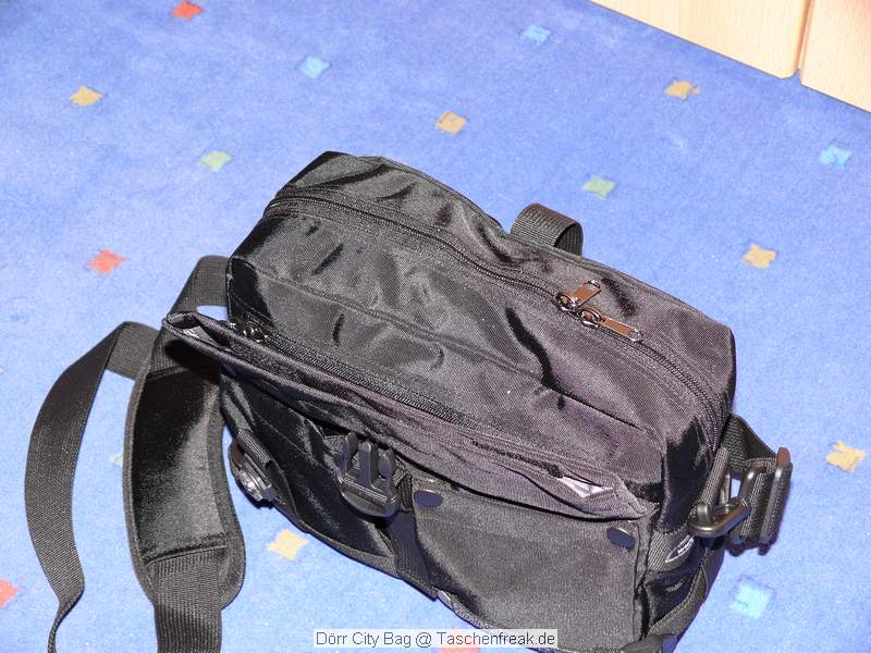 Dörr City Bag\n\nFoto von Jörg Langer\n\nKommentar des Nutzers:\n\nEine kleine Fototasche die nicht nach Fototasche aussieht und genau damit wird sie m.E. Ihrem Namen "City Bag" sehr gerecht.\n\nEs passen in dieses kleine Packwunder gut rein:\n\n- eine DSLR mit einem relativ großen Standardzoom wie einem 28-300er oder einem 18-200er oder ähnlichen Formfaktoren. Ein Canon 24-70 2,8L ist etwa 1 cm zu lang. In unserem "Packbeispiel hier haben wir ein 12-24 mit 82er Filterdurchmesser verwendet was deutlich größer ist als eins der genannten Reisezooms.\n\n- dazu eine 50er Festbrennweite und einen großen Systemblitz und Akkus dazu.\n\n- In die vielen kleinen und größeren Reisverschluss und Kletttaschen passen dann gut, Geldbörse, PDA, Handy und CF Cards sowie anderer Kleinkram rein.\n\nDier Tasche lässt sich sehr angenehm als Schulter- oder auch Torsotasche tragen.\n\nDer Preis ist mit 35 Euro vergleichsweise günstig und dadurch ist die Dörr City Bag auch gut als "Zweittasche" haltbar.\n\nDie Verarbeitung ist sehr hochwertig und sehr robust.\n\nDie Innentasche wird mit einem Kordelverschluss verzogen/verschlossen und dadurch ist die Cam auch relativ "Wasserfest" untergebracht.\n\nLeider passt auch das Equipment der Frau wie auf 2 Bildern zu sehen hervorragend hier rein, was den Innerfamiliären Konflikt "wer nutzt welche Tasche" nicht einfacher macht ;-)\n\nTaschenfreak Empfehlung: Sehr empfehlenswert!!!!