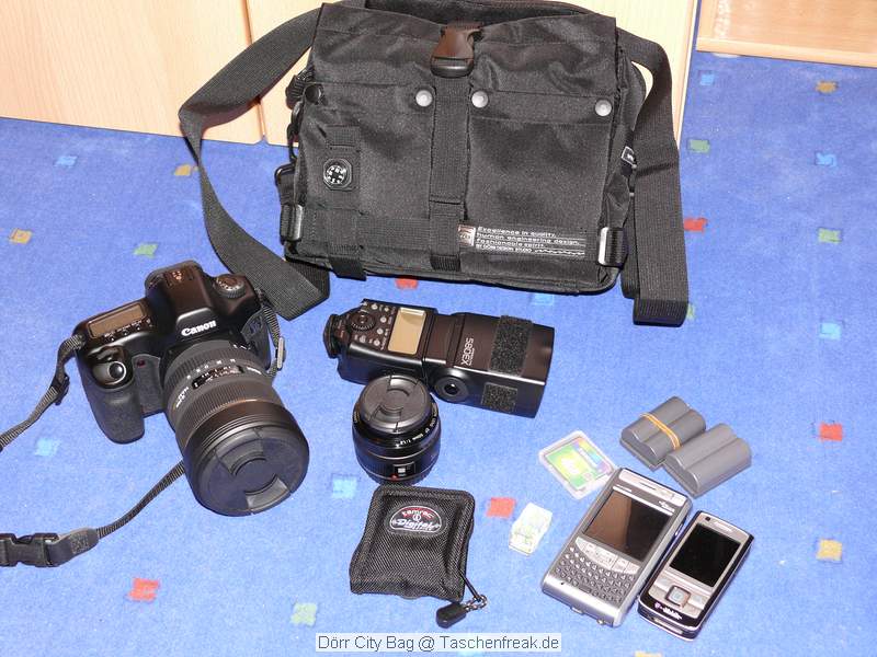 Drr City Bag\n\nFoto von Jrg Langer\n\nKommentar des Nutzers:\n\nEine kleine Fototasche die nicht nach Fototasche aussieht und genau damit wird sie m.E. Ihrem Namen "City Bag" sehr gerecht.\n\nEs passen in dieses kleine Packwunder gut rein:\n\n- eine DSLR mit einem relativ groen Standardzoom wie einem 28-300er oder einem 18-200er oder hnlichen Formfaktoren. Ein Canon 24-70 2,8L ist etwa 1 cm zu lang. In unserem "Packbeispiel hier haben wir ein 12-24 mit 82er Filterdurchmesser verwendet was deutlich grer ist als eins der genannten Reisezooms.\n\n- dazu eine 50er Festbrennweite und einen groen Systemblitz und Akkus dazu.\n\n- In die vielen kleinen und greren Reisverschluss und Kletttaschen passen dann gut, Geldbrse, PDA, Handy und CF Cards sowie anderer Kleinkram rein.\n\nDier Tasche lsst sich sehr angenehm als Schulter- oder auch Torsotasche tragen.\n\nDer Preis ist mit 35 Euro vergleichsweise gnstig und dadurch ist die Drr City Bag auch gut als "Zweittasche" haltbar.\n\nDie Verarbeitung ist sehr hochwertig und sehr robust.\n\nDie Innentasche wird mit einem Kordelverschluss verzogen/verschlossen und dadurch ist die Cam auch relativ "Wasserfest" untergebracht.\n\nLeider passt auch das Equipment der Frau wie auf 2 Bildern zu sehen hervorragend hier rein, was den Innerfamiliren Konflikt "wer nutzt welche Tasche" nicht einfacher macht ;-)\n\nTaschenfreak Empfehlung: Sehr empfehlenswert!!!!