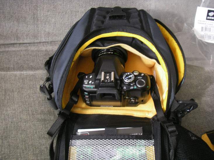 KATA H12\n\nFoto von Stefan W. aus Halle - VIELEN DANK!\n\nKommentar des Nutzers:\n\nHallo!\n\nIch htte noch ein paar Fotos zur KATA H-12, die zwar nicht so besonders sind, aber scheinbar fehlt die Tasche noch in Eurer Liste.\n\nDie abgebildete Kamera  auf den Fotos ist eine Olympus E-410 mit kurzer Festbrennweite.\nZur Tasche kann ich nicht so viel erzhlen, das Sie mir nicht gefallen hat.\nIm Vordergrund sieht man die "Regenhaut" und ein Teil fr den Transport von Normal-Akkus, die der Tasche beiliegen.\nDie Verarbeitung ist natrlich gut, aber warum die Tasche Testsieger geworden sein soll, bleibt mir ein Geheimnis.\nDer Clipverschluss ist durch die Hrte des Materials der Klappe sehr schlecht zu erreichen und ziemlich knibbelig, die Klappe ist so niedrig gezogen und dadurch die ffnung so tief, dass man bei geffneter Tasche Angst haben kann, dass die Kamera jeden Moment rausfllt. Besonders dann, wenn man vom beiligenden Trenner Gebrauch macht und im unteren Teil zum Beispiel noch ein weiteres kleines Objektiv o..  \nunterbringt.\nDer beiligende Gurt ist gut und schn gepolstert, allerdings durch das starre Schulterpolster ist es einem auch nicht mglich sich die Tasche eher auf den Rcken zu schieben.  Mittels der Kata-Tasche bzw. Gurt S-308 soll dies dann mglich sein, obwohl mich die Kombination mit dieser auch nicht berzeugen konnte.\nIn die Seitentaschen der H-12 kann man etwas Zubehr unterbringen, aber auf keinem Fall ein Objektiv o..\nwie es einem bei Betrachten der Kata-Homepage erscheinen mag. Das bezieht sich wohl nur auf das grere Modell.\n\nIch hoffe, das hilft soweit.