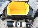 KATA WS-604\n\nFoto von Edgar Hermanns - VIELEN DANK!\n\nKommentar des Nutzers:\n\nAllgemeine Anmerkungen: \n\nPro: \n\n- Die Verarbeitung ist ber jeden Zweifel erhaben.\n- Vorteile gegenber den Loewe-Taschen: man kann die WS-604 auch mal in den Dreck stellen, sie hat Kunststofffsse, so dass sie nicht gleich in der Sosse steht. \n- Die Reissverschlsse sind Topqualitt.\n- Die Polsterung ist ppig.\n- Schlaufen fr Zusatzgepck, Anorak, Stativ o..\n\nContra: \n- Sehr teuer.\n- Packen erfordert etwas Phantasie, ein paar Zentimeter mehr Hhe wren fr mich persnlich besser gewesen.\n- der Schultergurt behindert ein wenig beim ffnen des Deckel-Reissverschlusses, die Karabinerhaken sind genau im Weg.\n\nMeine Bewertung: Top-Tasche mit Verbesserungsmglichkeiten im Detail. Zm Tragekomfort kann ich noch nichts sagen, der Hrtetest steht erst noch aus. Subjektiv fhlt sich mein ganze Germpel aber erst mal leichter an, als in der Slingshot 300.\n\nZum Packmodus: ich habe nur eine Konfiguration fotografiert. Wichtig war mir, dass die 5D auch mit angesetztem 70-200 reingeht. Das funktioniert auch, allerdings ist es dann besser, eine der beiden anderen Linsen in eine der Seitentaschen zu stecken (das geht). Insgesamt ist das ganz gut zu handhaben, ich kann die Kamera mit jeder meiner drei Linsen bestckt in der Tasche verstauen.\n\nDie Bilder:\n\nGeffnet, zum Vergleich 5D und 70-200 2.8 L IS. Passt so nicht rein.\n\nAlle Fotos © 2007 Edgar (emax) Hermanns, fotografiert mit Canon A710 IS.