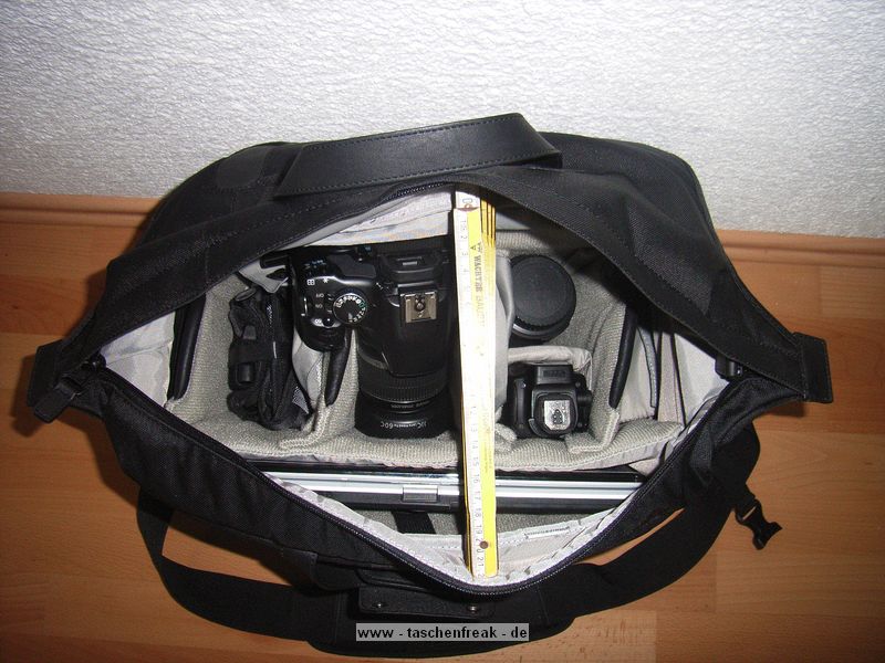 LOWEPRO CLASSIFIED 250AW\n\nFoto und Text von Ralf Steck - VIELEN DANK!\n\nKommentar:\n\nHallo Jörg,\n\nnachdem ich monatelang Deine Seiten durchgesehen habe, hier mal ein Beitrag von mir: Fotos zur Lowepro Classified 250AW. \n\nDie Tasche ist schon sehr groß, aber es geht eben auch viel rein. Ich bin freier Journalist und suchte nach einer Tasche für Laptop + Fotoausrüstung + Schreibmappe + Platz für Unterlagen, beispielsweise wenn ich auf Pressekonferenzen gehe. Im Kamerafach ist noch einiges an Platz, beispielsweise für ein Buch und Notklamotten, wenn’s mal wieder mit dem Flugzeug irgendwohin geht. Die Tasche ist allerdings offiziell zu groß fürs Handgepäck, gepackt wie auf den Bildern zu sehen sind die Maße 45 x 29 x 29, wobei es möglich sein sollte, die Tasche auf Handgepäcktaugliche 20cm Breite zu drücken, wenn die Schreibmappe draußen ist. Auf der Reise ist die Lasche fürs anbringen am Koffertrolley praktisch. Hinten dran ist nochmal ein frei zugängliches, mit Reißverschluss gesichertes Fach dran, in das A4-Unterlagen passen, aber beispielsweise auch Bordkarten, Pass usw. griffbereit und trotzdem sicher transportiert werden können.\n\nDas Fotofach und die Trenner sind komplett mit dem weichen Klettstoff belegt, so dass man die Tasche völlig frei einrichten kann, beispielsweise auch zweistöckig. Das EF-S 55-250 passt mit aufgesetzter Geli aufrecht rein, ebenso der Blitz (Canon Speedlite 580 EX-II) mit Bouncer drauf. Zwei Microfasertücher, die an kleinen, klettbaren Taschen sitzen, schützen die Kamera.\n\nDas linke vordere Fach ist innen mit samtartigem Stoff gefüttert, so dass der IPod schön sicher transportiert werden kann. Es ist noch eine Rolltasche für bis zu 9 CF-Karten dabei, die ich aber nicht benutze.\n\nDie Tasche sieht, wie ich finde, elegant, anzugtauglich und nicht fototaschenmäßig aus, auch wenn sie durch die große Tiefe schon etwas sperrig wirkt. Sie lässt sich angenehm tragen und ich habe sie auch schon mit dem Zusatzgurt auf dem Rad getragen. Dabei fällt auf, dass das Schulterpolster fest am Gurt ist, wenn man die Tasche auf den Rücken schiebt, hat man das Polster an der Brust statt oben auf der Schulter.\n\n--\nViele Grüße vom Bodensee,\nRalf Steck - Die Textwerkstatt