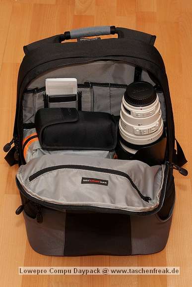 Foto von Jörg Langer\n\nRelativ großes Daypack Fach oberhalb des Kamerafaches. In diesem Fall der Beladung steht hier hochkannt ein Canon 100-400, daneben eine kleine Tasche mit Notebook Netzteil und Kabel, Steckernetzteil für XDRIVE und Sandisk Card Reader, darüber ein Blitzgerät in der originalen Hülle. In der vorderen inneren Reisverschlusstasche ist das XDRIVE und die Speicherkartenmappen enthalten.