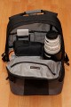 Foto von Jrg Langer\n\nRelativ groes Daypack Fach oberhalb des Kamerafaches. In diesem Fall der Beladung steht hier hochkannt ein Canon 100-400, daneben eine kleine Tasche mit Notebook Netzteil und Kabel, Steckernetzteil fr XDRIVE und Sandisk Card Reader, darber ein Blitzgert in der originalen Hlle. In der vorderen inneren Reisverschlusstasche ist das XDRIVE und die Speicherkartenmappen enthalten.