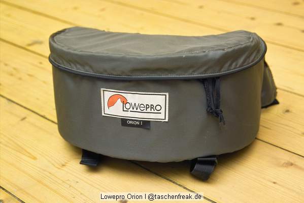 Foto von Ralf Neumann - VIELEN DANK!\n\nKommentar des Nutzers:\n\nOrion I\nDie ursprüngliche Version der Orion aus den 80ern. Relativ einfache aber robuste Hüfttasche. Nachteil ist der zum Körper hin klappende Deckel, der allerdings geschlossen den Vorteil hat mit hochgeklapptem Rand eine ganz gute, wenn auch etwas rutschige, Ablage zu bieten. Diese Tasche ist von Zeit zu Zeit unter 15 Euro in der Bucht zu haben.