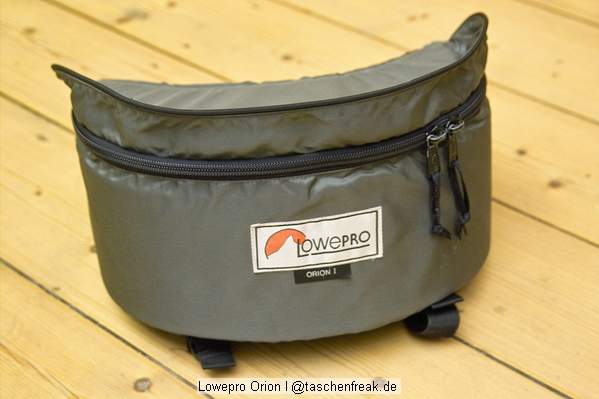 Foto von Ralf Neumann - VIELEN DANK!\n\nKommentar des Nutzers:\n\nOrion I\nDie ursprngliche Version der Orion aus den 80ern. Relativ einfache aber robuste Hfttasche. Nachteil ist der zum Krper hin klappende Deckel, der allerdings geschlossen den Vorteil hat mit hochgeklapptem Rand eine ganz gute, wenn auch etwas rutschige, Ablage zu bieten. Diese Tasche ist von Zeit zu Zeit unter 15 Euro in der Bucht zu haben.