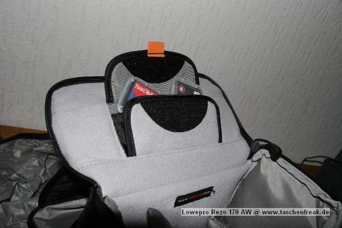 Foto von Markus Langen - DANKE DAFÜR !\n\nKommentar des Nutzers:\n\nDie Rezo Tasche ist eine kleine Tasche, die man sich über die Schulter hängen oder am Gürtel aufziehen kann. Sie ist Gedacht für eine kleine SLR (z.B. 20D) mit 2-3 Objektiven (bis ca 11,5 cm Länge) oder eine große Kompaktkamera (z.B. F828). Die Abkürzung AW steht für das All Weather System von Lowepro. Unter der Front der Tasche ist ein kleines Fach, indem sich ein Regencape für die Tasche befindet. Mann kann es schnell über die Tasche ziehen, das Kamerafach ist trotzdem ohne Probleme zu öffnen. Die Außentaschen sind mit von einem Überhang mit Lederimplantat geschützt. Um die Außentaschen zu öffnen muss dieser Überhang hochgeklappt  und der Reisverschluss geöffnet werden. Die Außentasche bietet genug Platz für Speicherkarten, Tücher, Objektivdeckel, Filterhüllen etc. \nDas Kamerafach ist weich ausgepolstert und wird von zwei Trennwänden in drei Fächer unterteilt. Da diese Trennwände mit Klettband befestigt werden, sind die Größen und Anordnung der Fächer individuell einstellbar.\nAn der Unterseite des Kamerafachdeckels ist ein kleines Fach, das ebenfalls zur Aufbewahrung von Speicherkarten genutzt werden kann.\n\nVerarbeitung:\n\nDie Tasche ist sehr gut und stabil vernäht . Allerdings haben sich an meiner Tasche die Nähte der Trennwände gelöst. (Bild)\n\nPro:\n\n- leicht\n- als Immerdabei Tasche geeignet\n- unauffällig\n- übersichtlich\n\nContra:\n\n- Nähte aufgegangen (oben erwähnt)