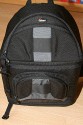 Lowepro Sling Shot 300AW\n\nFoto von Jrg Grunwald - DANKE DIR FR DIE BILDER!\n\nKommentar des Nutzers:\n\nDas Konzept der Lowepro Slingshot gefiel mir schon immer sehr gut, doch die Dinger waren zu klein.\n\nAm Freitag wurde dann meine neue Slingshot 300 AW von Directshopper.de geliefert.\n\nPlatz ist jetzt genug. Im Moment hab ich drin:\n\nNikon D2X, AF-S 70-200 / f2,8 VR, AF-S 18-200 VR, Tokina 12-24 ATX, Nikon SB 800 und noch ne Menge Kleinkram wie Fernauslser, Filter, usw. Zwei weitere Objektive normaler Gre wrden noch gut reinpassen.\n\nZusammen wiegt alles 5,8 KG. Das Gewicht ist mit der Slingshot noch sehr gut zu tragen, vor allem Dank des breiten gut gepolsterten Schultergurtes und der jetzt neu "richtigen" Beckengurte. Wenn man diese schn stramm einstellt, wird der Schultergurt ordentlich entlastet und die Tasche ist auch beim Laufen oder Klettern fest auf dem Rcken fixiert.\n\nFr den Zugriff auf die Cam braucht man nur den Verschlu des Beckengurtes zu lsen, die Tasche rutscht fast von selbst in die Zugriffsposition, dann noch schnell den gut laufenden Reiverschlu ffen und die Cam liegt griffbereit vor einem. Das ganze dauert mit ein bischen bung max. 5 Sekunden.\n\nEntgegen der blichen Beladung mit senkrecht stehenden Optiken im Hauptfach habe ich alles waagerecht bereinander, getrennt durch die Einteiler, in die Tasche gepackt. Das hat den Vorteil, das man in der Zugriffsposition an alle Teile von oben drankommt und die kleine ffnung ausreicht. Das finde ich besser, als bei Zugriff auf die Objektive erst den ganzen Deckel ffnen zu mssen. Einmal besteht das Risiko dass etwas herausfllt, zum anderen kann man in Zugriffsposition diesen Bereich nur schlecht einsehen, da er von einem selbst abgewandt ist. \nBesonders praktisch finde ich das im Zugriffsbereich fest eingenhte Mikrofasertuch z.B. zur Reinigung von Linsen.\n\nIn Summe fr mich eine sehr praktische, gerumige und gut zu tragende Tasche mittlerer Gre.\n\nXXX