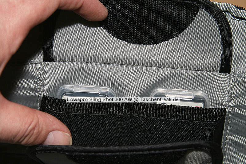 Lowepro Sling Shot 300AW\n\nFoto von Jörg Grunwald - DANKE DIR FÜR DIE BILDER!\n\nKommentar des Nutzers:\n\nDas Konzept der Lowepro Slingshot gefiel mir schon immer sehr gut, doch die Dinger waren zu klein.\n\nAm Freitag wurde dann meine neue Slingshot 300 AW von Directshopper.de geliefert.\n\nPlatz ist jetzt genug. Im Moment hab ich drin:\n\nNikon D2X, AF-S 70-200 / f2,8 VR, AF-S 18-200 VR, Tokina 12-24 ATX, Nikon SB 800 und noch ne Menge Kleinkram wie Fernauslöser, Filter, usw. Zwei weitere Objektive normaler Größe würden noch gut reinpassen.\n\nZusammen wiegt alles 5,8 KG. Das Gewicht ist mit der Slingshot noch sehr gut zu tragen, vor allem Dank des breiten gut gepolsterten Schultergurtes und der jetzt neu "richtigen" Beckengurte. Wenn man diese schön stramm einstellt, wird der Schultergurt ordentlich entlastet und die Tasche ist auch beim Laufen oder Klettern fest auf dem Rücken fixiert.\n\nFür den Zugriff auf die Cam braucht man nur den Verschluß des Beckengurtes zu lösen, die Tasche rutscht fast von selbst in die Zugriffsposition, dann noch schnell den gut laufenden Reißverschluß öffen und die Cam liegt griffbereit vor einem. Das ganze dauert mit ein bischen Übung max. 5 Sekunden.\n\nEntgegen der üblichen Beladung mit senkrecht stehenden Optiken im Hauptfach habe ich alles waagerecht übereinander, getrennt durch die Einteiler, in die Tasche gepackt. Das hat den Vorteil, das man in der Zugriffsposition an alle Teile von oben drankommt und die kleine Öffnung ausreicht. Das finde ich besser, als bei Zugriff auf die Objektive erst den ganzen Deckel öffnen zu müssen. Einmal besteht das Risiko dass etwas herausfällt, zum anderen kann man in Zugriffsposition diesen Bereich nur schlecht einsehen, da er von einem selbst abgewandt ist. \nBesonders praktisch finde ich das im Zugriffsbereich fest eingenähte Mikrofasertuch z.B. zur Reinigung von Linsen.\n\nIn Summe für mich eine sehr praktische, geräumige und gut zu tragende Tasche mittlerer Größe.\n\nXXX
