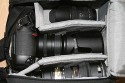Lowepro Sling Shot 300AW\n\nFoto von Jrg Grunwald - DANKE DIR FR DIE BILDER!\n\nKommentar des Nutzers:\n\nDas Konzept der Lowepro Slingshot gefiel mir schon immer sehr gut, doch die Dinger waren zu klein.\n\nAm Freitag wurde dann meine neue Slingshot 300 AW von Directshopper.de geliefert.\n\nPlatz ist jetzt genug. Im Moment hab ich drin:\n\nNikon D2X, AF-S 70-200 / f2,8 VR, AF-S 18-200 VR, Tokina 12-24 ATX, Nikon SB 800 und noch ne Menge Kleinkram wie Fernauslser, Filter, usw. Zwei weitere Objektive normaler Gre wrden noch gut reinpassen.\n\nZusammen wiegt alles 5,8 KG. Das Gewicht ist mit der Slingshot noch sehr gut zu tragen, vor allem Dank des breiten gut gepolsterten Schultergurtes und der jetzt neu "richtigen" Beckengurte. Wenn man diese schn stramm einstellt, wird der Schultergurt ordentlich entlastet und die Tasche ist auch beim Laufen oder Klettern fest auf dem Rcken fixiert.\n\nFr den Zugriff auf die Cam braucht man nur den Verschlu des Beckengurtes zu lsen, die Tasche rutscht fast von selbst in die Zugriffsposition, dann noch schnell den gut laufenden Reiverschlu ffen und die Cam liegt griffbereit vor einem. Das ganze dauert mit ein bischen bung max. 5 Sekunden.\n\nEntgegen der blichen Beladung mit senkrecht stehenden Optiken im Hauptfach habe ich alles waagerecht bereinander, getrennt durch die Einteiler, in die Tasche gepackt. Das hat den Vorteil, das man in der Zugriffsposition an alle Teile von oben drankommt und die kleine ffnung ausreicht. Das finde ich besser, als bei Zugriff auf die Objektive erst den ganzen Deckel ffnen zu mssen. Einmal besteht das Risiko dass etwas herausfllt, zum anderen kann man in Zugriffsposition diesen Bereich nur schlecht einsehen, da er von einem selbst abgewandt ist. \nBesonders praktisch finde ich das im Zugriffsbereich fest eingenhte Mikrofasertuch z.B. zur Reinigung von Linsen.\n\nIn Summe fr mich eine sehr praktische, gerumige und gut zu tragende Tasche mittlerer Gre.\n\nXXX