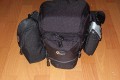 Foto von Jrg Langer\n\nKommentar des Nutzers:\n\nDie Toploader Serie von Lowepro ist sehr gut und hochwertig verarbeitet.\n\nIn dieses hier gezeigte Modell kann man Problemlos eine groe DSLR wie eine Canon 1D und ein All Round Zoom hineinpacken. Eine Schnellwechselplatte oder ein sogenannter L-Winkel passen auch geradeso noch hinein. Die Gegenlichtblende des Objektives sollte umgedreht montiert werden.\n\nIn der Vordertasche kann man entweder 2 groe Akkupacks oder einen mittelgroen Blitz reinpacken. Canon 420EX oder 430EX passen prima hinein, die groen 550EX oder 580EX sind etwa 1,5cm zu lang fr diese Vordertasche.\n\nAn den Seiten finden sie die Lowepro Sliplock Schlaufen an denen man gut seiten taschen oder eine Getrnkeflasche anbringen kann.\n\nIch setze hier gerne die LP D-Res25 an in der sich mein Polfilter udn 2 Akkupacks und ein paar Ersatzspeichercards befinden und auf der anderen Seite das kleine LP D-Res 8-S in dem sich meine Immerdabei Cam die Fuji F10 befindet.\n\nEine AW (Allwetterhlle) bzw. der Regenschutz befindet sich in der Fronttasche und kann auch wie abgebildet schnell und unkompliziert angebracht werden.\n\nFazit: Eine klasse Tasche fr das leichte "Sturmgepck". Bei mir gerne fr Feuerwehreinstze genutzt, weil ich da nichts auer meiner 1D und dem 24-105L und ab und zu einem kl. Blitz brauche.