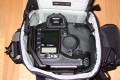 Foto von Jrg Langer\n\nKommentar des Nutzers:\n\nDie Toploader Serie von Lowepro ist sehr gut und hochwertig verarbeitet.\n\nIn dieses hier gezeigte Modell kann man Problemlos eine groe DSLR wie eine Canon 1D und ein All Round Zoom hineinpacken. Eine Schnellwechselplatte oder ein sogenannter L-Winkel passen auch geradeso noch hinein. Die Gegenlichtblende des Objektives sollte umgedreht montiert werden.\n\nIn der Vordertasche kann man entweder 2 groe Akkupacks oder einen mittelgroen Blitz reinpacken. Canon 420EX oder 430EX passen prima hinein, die groen 550EX oder 580EX sind etwa 1,5cm zu lang fr diese Vordertasche.\n\nAn den Seiten finden sie die Lowepro Sliplock Schlaufen an denen man gut seiten taschen oder eine Getrnkeflasche anbringen kann.\n\nIch setze hier gerne die LP D-Res25 an in der sich mein Polfilter udn 2 Akkupacks und ein paar Ersatzspeichercards befinden und auf der anderen Seite das kleine LP D-Res 8-S in dem sich meine Immerdabei Cam die Fuji F10 befindet.\n\nEine AW (Allwetterhlle) bzw. der Regenschutz befindet sich in der Fronttasche und kann auch wie abgebildet schnell und unkompliziert angebracht werden.\n\nFazit: Eine klasse Tasche fr das leichte "Sturmgepck". Bei mir gerne fr Feuerwehreinstze genutzt, weil ich da nichts auer meiner 1D und dem 24-105L und ab und zu einem kl. Blitz brauche.