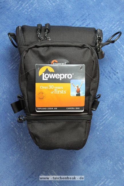 LOWEPRO - TOP LOADER ZOOM AW\n\nFoto von Peter Albrecht - VIELEN DANK!\n\nKommentar:\n\n- gekauft Januar 2009 (scheint auch berarbeitete Version zu sein gegenber dem Model, welches auch auf taschenfreak gezeigt wird)\n  neu: - Reisverschlu innen im Deckel hat jetzt eine Schutzkappe (Bild 06)\n       - SlipLock auf beiden Seiten (Bilder 02 und 04)\n\n- Beigaben:\n  - Schultergurt (Bild 05)\n  - Chest Harness (4 Kunststoffhaken) (Bild 05)\n      - Chest Harness, den man als extra Zubehr erwerben kann hat fr die oberen Ringe zwei Metallhaken\n      - Gurte lassen sich schnell und einfach verstellen\n      - keine Anleitung => erst mal experimentieren, aber man kriegs relativ schnell hin\n  - klitzekleine Anleitung fr die Tasche selbst (englisch / franzsisch / kein Deutsch)\n  - Werbeschild 30 Jahre Lowepro (ist dann wohl schon etwas lter) (Bild 01)\n\n- Innenraum mit 4 Trennern veriabel gestaltbar (Bilder 05, 07, 08 und 09)\n- beim 18-55mm Objektiv kann man problemlos das Ladegert fr die Akkus unter einem doppelten Boden verstauen (Bild 09)\n- die zwei groen Trenner haben noch seitliche Taschen fr Kleinzeugs (z.B. Akkus) (Bilder 05 und 08)\n- Zwei SlipLock Schlaufen (je eine links und rechts) (Bilder 02 und 04)\n- die oberen zwei Ringe zur Befestigung des Tragesystems sind aus Metall, die unteren aus Kunststoff, aber die sind ja nicht so wichtig.\n\n- Was geht rein?\n  - Canon 500D mit Batteriegriff und Tragegurt (Bild 06)\n  - Speedlite 430 EX II + Ersatzakkus + Zweitakku fr Camera (Bild 08)\n  - Ladegert (Bild 09)\n  - Zettel und Speicherkarte (Bild 10)\n  - Anleitungen fr Speedlite und 500D, Stifte, Taschenlampe (Bild 11)\n  - Mignon-Halter fr den Batteriegriff - aber UNGEPOLSTERT! (Bild 12)\n\n\n- All-Weather-Cover (AWC): (Bilder 13 - 16)\n  - Ringe und Gurtschlaufe fr Tragesysteme bleiben frei\n  - Deckel, Fronttasche, Seitentasche sind eingepackt (kein Zugang)\n  - SlipLock auch bei AWC verwendbar\n  - Tragsystem mu vor dem Aufziehen des AWC nicht entfernt werden\n  - Seite am Krper und die Hlfte der linken/rechten Seite (Sliplock) bleiben frei\n  - AWC ber langes Band fest mit Tasche vernht -> kein Verlieren\n\nNegativ:\n- Toploader-Deckel (geschwungen) pat zur Kamera-Form (eher flach) (Bild 17)\n- Blitznase spreitzt sich beim Einlegen an Klettverschlubasis (mit der Zeit lernt man aber, wie mans gut rein bringt)\n- Klettverschlu fr Innenraumteiler aufgenht -> sieht nicht so toll aus und man kann beim Einpacken daran hngen bleiben (EOS 500D) (Bilder 07 und 08)\n- Im Vergleich zum Toploader Pro 70 AW hat der Zoom AW eher ein Plastik-Feeling (besonders die Tasche im Deckel) (Bild 09)\n- Fronttasche garnicht gepolstert -> keine empfindlichen Sachen verstauen\n - im oberen Teil ist das AWC zwischen Tascheninhalt und auen (Bild 11)\n - unten gibts nur ein ungepolstertes Stck Stoff, den Mignon-Halter fr den Batteriegriff sollte man da NICHT transportiern (Bild 12)