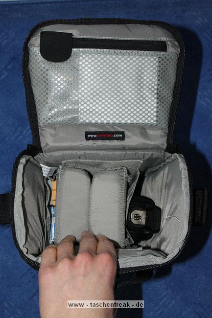 LOWEPRO - TOP LOADER ZOOM AW\n\nFoto von Peter Albrecht - VIELEN DANK!\n\nKommentar:\n\n- gekauft Januar 2009 (scheint auch überarbeitete Version zu sein gegenüber dem Model, welches auch auf taschenfreak gezeigt wird)\n  neu: - Reisverschluß innen im Deckel hat jetzt eine Schutzkappe (Bild 06)\n       - SlipLock auf beiden Seiten (Bilder 02 und 04)\n\n- Beigaben:\n  - Schultergurt (Bild 05)\n  - Chest Harness (4 Kunststoffhaken) (Bild 05)\n      - Chest Harness, den man als extra Zubehör erwerben kann hat für die oberen Ringe zwei Metallhaken\n      - Gurte lassen sich schnell und einfach verstellen\n      - keine Anleitung => erst mal experimentieren, aber man kriegs relativ schnell hin\n  - klitzekleine Anleitung für die Tasche selbst (englisch / französisch / kein Deutsch)\n  - Werbeschild 30 Jahre Lowepro (ist dann wohl schon etwas älter) (Bild 01)\n\n- Innenraum mit 4 Trennern veriabel gestaltbar (Bilder 05, 07, 08 und 09)\n- beim 18-55mm Objektiv kann man problemlos das Ladegerät für die Akkus unter einem doppelten Boden verstauen (Bild 09)\n- die zwei großen Trenner haben noch seitliche Taschen für Kleinzeugs (z.B. Akkus) (Bilder 05 und 08)\n- Zwei SlipLock Schlaufen (je eine links und rechts) (Bilder 02 und 04)\n- die oberen zwei Ringe zur Befestigung des Tragesystems sind aus Metall, die unteren aus Kunststoff, aber die sind ja nicht so wichtig.\n\n- Was geht rein?\n  - Canon 500D mit Batteriegriff und Tragegurt (Bild 06)\n  - Speedlite 430 EX II + Ersatzakkus + Zweitakku für Camera (Bild 08)\n  - Ladegerät (Bild 09)\n  - Zettel und Speicherkarte (Bild 10)\n  - Anleitungen für Speedlite und 500D, Stifte, Taschenlampe (Bild 11)\n  - Mignon-Halter für den Batteriegriff - aber UNGEPOLSTERT! (Bild 12)\n\n\n- All-Weather-Cover (AWC): (Bilder 13 - 16)\n  - Ringe und Gurtschlaufe für Tragesysteme bleiben frei\n  - Deckel, Fronttasche, Seitentasche sind eingepackt (kein Zugang)\n  - SlipLock auch bei AWC verwendbar\n  - Tragsystem muß vor dem Aufziehen des AWC nicht entfernt werden\n  - Seite am Körper und die Hälfte der linken/rechten Seite (Sliplock) bleiben frei\n  - AWC über langes Band fest mit Tasche vernäht -> kein Verlieren\n\nNegativ:\n- Toploader-Deckel (geschwungen) paßt zur Kamera-Form (eher flach) (Bild 17)\n- Blitznase spreitzt sich beim Einlegen an Klettverschlußbasis (mit der Zeit lernt man aber, wie mans gut rein bringt)\n- Klettverschluß für Innenraumteiler aufgenäht -> sieht nicht so toll aus und man kann beim Einpacken daran hängen bleiben (EOS 500D) (Bilder 07 und 08)\n- Im Vergleich zum Toploader Pro 70 AW hat der Zoom AW eher ein Plastik-Feeling (besonders die Tasche im Deckel) (Bild 09)\n- Fronttasche garnicht gepolstert -> keine empfindlichen Sachen verstauen\n - im oberen Teil ist das AWC zwischen Tascheninhalt und außen (Bild 11)\n - unten gibts nur ein ungepolstertes Stück Stoff, den Mignon-Halter für den Batteriegriff sollte man da NICHT transportiern (Bild 12)