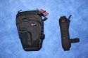 LOWEPRO TOPLOADER PRO 70 AW\n\nFoto und Text von Peter Albrecht - VIELEN DANK!\n\nKommentar:\n\n- gekauft Januar 2009 (vermutlich der Nachfolger des "Toploader 70 AW" - ohne "Pro")\n  - Unterschied zum "ohne Pro": \n     - Deckel klappt jetzt nach links weg anstatt nach vorne.\n     - hat nur noch auf einer Seite (links) Sliplock-Erweiterungsmglichkeit\n     - statt der Sliplock rechts, gibts jetzt eine Auentasche, die mit Gummi oben "gesichert" ist\n		- es gibt aber (Stand Januar 2009) auch noch den "ohne Pro" frs gleiche Geld im Internet\n\n- Beigaben:\n  - Dreipunkt Gurt zum tragen (Bild 01)\n  - klitzekleine deutsche Anleitung\n  - Werbeschild 40 Jahre Lowepro (mte der Aktuelle Stand sein)\n\n- Camera (500D) sitzt fest in der Tasche\n- Innenraum mit 2 Trennern verstellbar (Bilder 09, 10 und 11)\n- bleibt grundsttzlich sogar aufrecht stehen (ist aber nicht besonders stabil, besser hinlegen)\n- Karabiner des Schultergurtes aus Metall\n- mit ein bichen Gefummel, kann man auch die Cameratasche fr die PowerShot in der SlingShot Schlaufe einhngen (Bild 18)\n- Schnellverschlu (keine Reisverschlsse notwendig, um nur die Kamera zu halten)\n- Cameragurt kann man entweder mit in die Tasche rein packen (Bilder 07 und 08), oder raus hngen lassen und ggf in die \n Auentasche packen (Bilder 05 und 06).\n\n- Was pat rein? (Bild 16)\n  - Canon 500D mit Batteriegriff und Tragegurt (Bilder 05 und 07)\n  - Ladegert (unter doppeltem Boden) (Bild 12)\n  - Mignon-Halter fr den Batteriegriff (Bild 13)     - \n  - Speedlite 430 EX II + Zweitakku fr Camera (Bild 14)\n  - Zettel, Speicherkarte, Blitz Ersatzakkus, Anleitungen fr Speedlite und 500D  (Bild 15)\n  - Stifte (Bild 17)\n  - (PowerShot, aber ungepolster) (Bild 17)\n\n- All-Weather-Cover (AWC): (Bilder 20 bis 23)\n  - Ringe und Gurtschlaufe fr Tragesysteme bleiben frei\n  - Deckel lt sich ffnen (wrd ich bei strmenden Regen nicht machen)\n  - Fronttasche, Seitentasche sind zugepackt (kein Zugang)\n  - SlipLock und AWC sind NICHT gleichzeitig verwendbar\n  - Tragsystem mu vor dem Aufziehen des AWC entfernt werden\n  - Nur die Seite am Krper bleibt frei\n  - AWC ber langes Band fest mit Tasche vernht -> kein Verlieren\n\nNegativ:\n- Anleitung fr Schultertragegurt fehlt. (siehe http://www.lowepro-deutschland.de/videos/flvplayer/video_toploader.html)\n- nur eine Sliplock Schlaufe (linke Seite vom Krper aus gesehen)\n- beim Tragen am 3-Punkt-Gurt ist der Toploader bei den ersten Versuchen dem linken Arm im Weg. Vielleicht findet sich durch etwas experimentieren eine bessere Position.\n\nKombination mit dem "Lowepro Chest Harness" ist nicht bequem!\n- Da der Toploader-Deckel nach links aufgeht, sind die oberen Ringe frs Tragesystem sehr nah am Krper; \n Beim Tragen am Chest Harness kippt der obere Teil der Tasche dadurch nach vorne weg, da das Tragesystem keinen\n Zug zum Kper hin erzeugen kann. Dies wiederum resultiert darin, da die untere Kante der Tasche in den \n Bauch drckt, anstatt da das ganze Rckenteil der Tasche flach aufliegt. Dadurch ist das Tragen am Chest\n Harness nicht ganz so bequem. (Der "Toploader Zoom AW" z.B. schmiegt mit dem Chest Harness viel angenehmer \n an den Brustkorb)\n- Besser: Toploader mit kleinen Karabinern an einem Rucksack festmachen. (Bild 19). Vielleicht ist auch der \n "Tamrac S-500 Chest Harness System" geeignet. Auf dem Produktbild sieht es jedenfalls so aus.