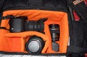 NANEU PRO ALPHA\n\nFoto von Roger Wimbert - VIELEN DANK!\n\nKommentar des Nutzers:\n\nHallo,\n\nauch ich mchte mich herzlich fr Deine Arbeit bedanken. Nach langer berlegung und mehreren Versuchen (u.a. Tamrac Velocity 8x, LowePro Fastpak 200) habe ich mir nun eine Naneu Alpha angeschafft. Mein Problem mit den anderen Taschen war, dass die Einteilung einfach zu unflexibel ist. Die Kamerafcher sind fr meine Pentax K100D super einfach zu gro. \nBei der Naneu ist das Kamerafach wirklich beliebig teilbar, so dass eine kleine Kamera mit groem Objektiv (Sigma 17-70 plus Sonnenblende in\nArbeitsstellung) problemlos fest verstaubar ist. Allerdings mit dem Nachteil, dass ich unterwegs nicht an die Ausrstung komme. Dafr gibt es aber am Bauchgurt Schlaufen, an denen ich Objektivkcher befestigen kann, um die aktuell verwendeten Objektive schnell wechseln zu knnen.\n\nberrascht hat mich, dass bei meinem Rucksack eine Regenhaube (in einer Netztasche, die auch als Flaschenbehlter dienen kann, siehe Bild) geliefert wurde. Diese Regenhaube ist eigentlich nur bei den Modellen in Tarnfarbe enthalten.\n\nNun zur Ausrstung: Es gehen hinein:\nPentax K100D super mit Sigma 17-70 inkl. Sonnenblende, links unten Sigma 4-5.6/70-300 inkl. Sonnenblende, alternativ wrde Pentax DA 10-17 und DA 50-200 bereinander hineingehen, rechts daneben Pentax DA 50-135 inkl. \nSonnenblende, auf der rechten Seite der Sigma EF 500 Super Blitz. Unter dem Blitz finden noch einige kleine Objektive Platz, hier Pentax F 1.7/50 und DA 10-17.\n\nIn der Vordertasche sind mehrere Stze Batterien, Stifte, Fernauslser, Reflektoren und Graukarte untergebracht. Im Hauptfach passt eine 0,5l-Flasche stehend hinein. Ein Sixpack wrde somit passen. An der Aussenseite ist ein kleines Reisestativ befestigt.\n\nAm Bauchgurt sind an jeder Seite zwei Schlaufen fr weiteres Zubehr (hier die Netztasche mit einer 0,5l-Flasche).\n\nInsgesamt bin ich sehr zufrieden mit dem Rucksack, wenn auch die Handy-Tasche sehr hoch sitzt.\n\nRoger Wimbert