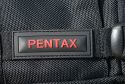 PENTAX X-BAG\n\nFoto und Kommentar von Olaf Mokansky - VIELEN DANK!\n\nKommentar:\n\nHallo Taschenfreak,\n\nleider ist dieser Rucksack in Deutschland kaum verfgbar/bekannt. Es \nhandelt sich um ein umgelabeltes Exemplar des Naneu Echo Pro mit \nfarblich auf Pentaxrot abgestimmtem Kamerateil und schwarzem \nAuenstoff.\n\nDas Material ist ber jeden Zweifel erhaben, die Verarbeitung top und \ndas Ganze extrem leicht.\n\nDie Vordertaschen haben keinen Deckel da sollte also nichts \nfeuchtigkeitsempfindliches rein. Ansonsten sind die meisten \nReiverschlsse (leider nicht der vom flachen Vorderfach) abgedeckt.\n\nDas Kamerafach kann man sich frei einteilen, es sind reichlich \nEinteilungen vorhanden, die beliebig angeordnet werden knnen. Und \nobwohl das Ganze nicht nur auf den Fotos recht klein aussieht sondern \nauch im Original, hatte ich keine Probleme, meine gesamte Ausrstung \n(okay, fast die ganze) unterzubringen.\nPentax K-m mit 40er Limited, 12-24er Pentax, 18-55 Kit-Pentax, 55er \nNikkor mit Adapter und Zwischenringen, Lochblende und Polfilter, \nAkkus, Speicherkarten. Wahlweise lsst sich das Macro durch ein Tele \nersetzen, oder das 18-55 bleibt zuhause.\nIm oberen Teil ist Platz fr eine Thermoskanne (1 Liter), Verpflegung, \nKartenmaterial, fr lngere Radtouren gibts ein extra iPod-Fach mit \nKopfhrerausgang.\n\nDie ersten Anproben versprechen einen guten rutschfesten Sitz