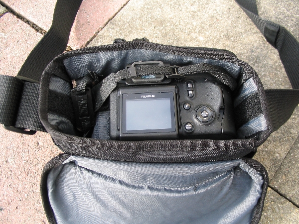 TAMRAC 5533- ADVENTURE MESSENGER 3\n\nFoto von Udo Boesch - Vielen Dank!\n\nKommentar des Nutzers:\n\nHallo Jrg Langer,\n \nich habe ein paar Bilder von einer Tamrac Adventure Messenger 3 Tasche. Es wrde mich sehr freuen, wenn du sie bei dir in deiner Page aufnehmen wrdest.\n \nHier ein paar Infos dazu:\n \nDie Tamrac-Adventure-Messenger-3 Fototasche bietet laut Hersteller Platz fr eine Spiegelreflex mit aufgesetztem Objektiv bis zu 12,5cm Lnge. Ich besitze eine Bridgekamera Fuji S9600, diese passt wirklich prima hinein. Das Hauptfach selbst ist mit 2 verstellbaren, schaumstoffgepolsterten Unterteilungen ausgestattet. Diese knnen mit Klettverschlssen individuell angepasst werden, so passt wirklich jede Kamera, egal wie breit in die Tasche. Selbstverstndlich knnen auch links und rechts Zusatzblitz oder zustzliche Objektive verstaut werden. Die Tasche bietet den Vorteil, dass hier kleine mit Klettverschluss bestckten schaumstoffgepolsterten Zwischenbden eingebracht werden knnen. So liegt das Objektiv geschtzt auf diesem Zwischenteil auf.\n \nDie Vortasche wird mit Reissverschlssen gesichert und beinhaltet 2 Einsteckfcher. Im Deckel befindet sich ein reissverschlussgesichertes flaches Einsteckfach.\nSeitlich (li + re) sind aufgesetzte Taschen, einmal mit Klettverschluss fr Handy o., auf der anderen Seite ohne Klettverschluss.\nAn der Rckwand ist ebenfalls eine aufgesetzte Tasche mit Reissverschluss, ideal fr eine Bedienungsanleitung o..\nDer Umhngegurt ist schn breit und mit einem rutschsicherem Schulterpolster versehen. Desweiteren hat die Tasche einen EasyGrip Tragegriff. \n \nDie Mae der Tasche lt. Hersteller:\nAuenmae: 23 x 23 x 14 cm (BxHxT)\nInnenmae: 20 x 20 x 10 cm (BxHxT) \nGewicht: 630 g\n \nHinweis: Alle Reissverschlsse sind regengeschtzt.\n \nFolgen Farben sind mglich: Camouflage, rot/schwarz und grau/schwarz.\n \nPreis: 39,90 \n \n \nInfos zu den einzelnen Bildern.\n \nBild 1: Frontansicht der Tasche (Camouflage) mit Tragegurt\nBild 2: Rckansicht der Tasche mit Reissverschlussfach fr Bedienungsanleiung\nBild 3: Seitenansicht mit Handyfach\nBild 4: Innenfach mit Kamera darin\nBild 5: Vortasche mit den zwei Einsteckfchern.\nBild 6: Vortasche mit den zwei Einsteckfchern\nBild 7: Hauptfach mit den zwei verstellbaren, schaumstoffgepolsterten Unterteilungen\nBild 8: Unterteilungen mit Klettverschluss verstell- und individuell anpassbar.\nBild 9: Hauptfach mit Kamera darin.\nBild 10: Tasche Frontansicht mit Verschluss\nBild 11: Gepolsterter rutschsicherer Tragegurt mit Polster (Innenseite)\nBild12: Gepolsterter rutschsicherer Tragegurt mit Polster (Aussenseite)