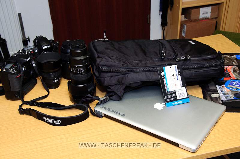 THINK TANK PHOTO - SHAPE SHIFTER\n\nFoto und Kommentar von Jörg Langer - www.taschenfreak.de\n\nKommentar:\n\nDer Shape Shifter, den wir freundlicherweise von ISARFOTO für einen Bericht und Test für Euch liebe Pagebesucher, zur Verfügung gestellt bekommen haben, löst bei uns den WOW Effekt aus.\n\nSehr schmal bzw. flach liegt er da auf dem Tisch und man fragt sich wie man das ganze Zeugs da rein bekommen soll ...\n\nLaut Hersteller sind 17" Notebook plus dessen Zubehör, 2x Profibodys, 3x 2.8er Profilinsen und jede Menge Zubehör kein Problem für dieses Teil.\n\nRECHT HAT ER DER HERSTELLER! Null Problem das alles darin zu verstauen und dennoch wirklich sehr bequem auf dem Rücken zu tragen.\n\nWas haben wir mal eben darin verstaut:\n\nBody D3\nBody D300 mit BG\n17-35 2.8\n24-70 2.8\n70-200 2.8\n85 1.4\nSB-900\nMBP 17" Unibody (wenn es eins gäbe würde auch ein 19" passen ...)\nNetzteil MBP, Maus, u.v.m.\n\nDie im Hauptfach beindlichen Neopren einzelhüllen sind grandios, sehr flexibel und dennoch hochschützend für das Equipment. Wir hatten vor einigen Monaten auch mal den Stealth Reporter II vom anderen großen Taschenhersteller - glaubt uns bitte - es liegen WELTEN dazwischen in der Verarbeitung des inneren und äußeren dieses Shape Shifters!\n\nWenn man das Fotofach nicht nutzt kann man den Rucksack als reinen Notebookrucksack mit einem umlaufenden Reissverschluss smarter und flacher machen - ein sicher sehr nützliches Detail wenn man Abends das ganze Fotozeugs im Hotel lässt und die Agentur oder die Kollegen mit dem Notebook aufsucht. \n\nJede Menge Kleinkram und persönliches was man so braucht und auch noch 2 weitere Blitze wären kein Problem - und das faszinierende: ES TUT NICHT WEH auf dem Rücken - der Shape Shifter bleibt sehr bequem und durch seinen eigentlich weichen Aufbau ist er sehr angenehm und nirgends störend auf dem Rücken - also auch während dem "Paparazzen" kann man diesen Rucksack aufbehalten.\n\nFazit: Wer Reportageartig fotografiert findet hier sein Werkzeug - ganz sicher!