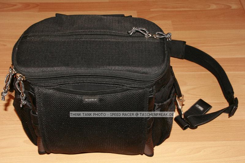 THINK TANK PHOTO - SPEED RACER\n\nFoto von Thomas Brocher - VIELEN DANK!\n\nKommentar des Nutzers:\n\nDer SpeedRacer ist so ziemlich die einzige Toploader-Tasche f�r mehr als nur die Kamera mit 1 Objektiv. Bei mir passt hinein rechts ein 10-22, links ein 24-105, in die Mitte ein an die 1D angesetztes 100-400. Vorne in die Fronttasche geht problemlos mein 430EX Blitz hinein. Durch einen Rei�verschluss im Deckel kann man schon mal auf Kleinigkeiten zugreifen ohne den ganzen Deckel �ffnen zu m�ssen.\nF�r den Transport bei Wanderungen oder Fahrradtouren kann ein d�nner aber breiter Beckengurt aus der R�ckwand seitlich gezogen werden. Im Gegensatz zu anderen Beckengurten kann dieser wirklich so vertaut werden, dass er kaum auff�llt und die Tasche dann nur noch nach Tasche "ohne das Gebummels" aussieht.\nDer Tragegurt ist sehr gut gepolstert, die �sen sind aus Metall. �berhaupt ist die Tasche sehr hochwertig verarbeitet, was sich allerdings auch im Preis von 160,- � bei IsarFoto niederschl�gt.