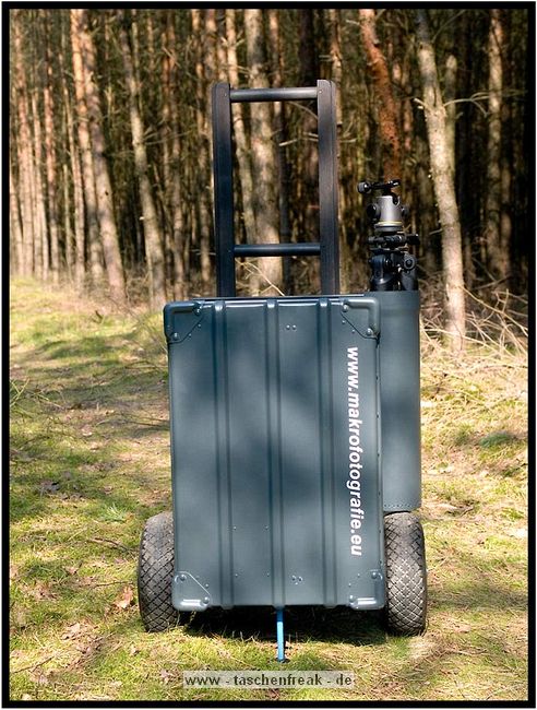 ZARGES TRANSPORTWAGEN - SELBSTBAU\n\nFoto und Text von Thomas Bder - VIELEN DANK!\n\nKommentar:\n\nTransport der Fotoausrstung\n\n \n\nNun ist es endlich soweit.\n\nLange habe ich an diesem Transportwagen geplant und gebaut.\n\nAuch wenn es vielleicht nicht so aussieht :-)\n\nBasis des Ganzen ist eine 60l Zarges Aluminiumkiste von der Bundeswehr.\n\nQuasi unkaputtbar und absolut wasserdicht.\n\nDie rckseitige Konstruktion besteht aus Aluminium und Eschenholz.\n\nHolz deshalb, weil es schn warm ist im Winter, man keine Schweihnde bekommt und Schlge gut abfedert werden.\n\nDie Eschenprofile sind als Nut und Feder ausgefhrt, damit man den Transportgriff ausziehen kann.\n\nIn die inneren Profile sind gefederte Bolzen eingebaut, die durch einen kleinen Seilzug nach innen gezogen werden knnen.\n\nDamit wird der Teleskopgriff entriegelt.\n\nDie weien Punkte an den Profilen, markieren die Einrastpositionen.\n\nUnten ist die Parkposition.\n\nNach oben hin gibt es Endanschlge aus Alu und Hartgummi, falls die Bolzen mal versagen sollten.\n\nDie luftgefllten Rder laufen auf einer 20mm Stahlrohrachse.\n\nDas blaue Beinchen unten, ist abschraubbar und nur fr den aufrechten Stand notwendig.\n\nBlau deshalb, um es im Ernstfall im Wald wiederzufinden ;-)\n\nAn einer Seite befindet sich die Halterung fr das Stativ.\n\nDieses Rohr hat unten ein eingeflochtenes Nylongarnnetz um das Stativ abzufedern und auch Wasser durchlaufen zu lassen.\n\nDie Stativhalterung ist innerhalb von Sekunden komplett abnehmbar, falls man kein Dreibein bentigt.\n\nDie beiden grauen Winkel mit den roten Kappen sind die Beine fr die liegende Position.\n\nIn der Box selbst gibt es zwei verstellbare Alutrennwnde.\n\nLinks und rechts befindet sich jeweils ein Einsatz einer Lowepro Stealth Reporter 500 AW Tasche.\n\nDiese 500er Taschen benutze ich normalerweise und kann somit wunderbar hin und her tauschen.\n\nIn der Mitte stehen einfach vier groe Objektivbecher nebeneinander.\n\nPlatz ist also mehr als genug...\n\nNun noch ein paar Daten:\n\nZum Zerlegen braucht man einen 4er und einen 6er Inbusschlssel, einen 13er Maulschlssel und einen normalen Kreuzschlitzschraubendreher.\n\nGewicht ca. 14kg also so ungefhr auf Pelicase Niveau nur mit dickeren Reifen :-)\n\nMae:\n\n60cm breit, 36cm tief, 73cm hoch (ohne Griff), mit ausgezogenem Griff 122cm\n\nInnenmae der Kiste:\n\n56cm breit, 37cm tief, 22cm hoch\n\nLink:\nhttp://www.makrofotografie.eu/index.php?option=com_content&view=article&id=47&Itemid=54