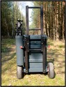 ZARGES TRANSPORTWAGEN - SELBSTBAU\n\nFoto und Text von Thomas Bder - VIELEN DANK!\n\nKommentar:\n\nTransport der Fotoausrstung\n\n \n\nNun ist es endlich soweit.\n\nLange habe ich an diesem Transportwagen geplant und gebaut.\n\nAuch wenn es vielleicht nicht so aussieht :-)\n\nBasis des Ganzen ist eine 60l Zarges Aluminiumkiste von der Bundeswehr.\n\nQuasi unkaputtbar und absolut wasserdicht.\n\nDie rckseitige Konstruktion besteht aus Aluminium und Eschenholz.\n\nHolz deshalb, weil es schn warm ist im Winter, man keine Schweihnde bekommt und Schlge gut abfedert werden.\n\nDie Eschenprofile sind als Nut und Feder ausgefhrt, damit man den Transportgriff ausziehen kann.\n\nIn die inneren Profile sind gefederte Bolzen eingebaut, die durch einen kleinen Seilzug nach innen gezogen werden knnen.\n\nDamit wird der Teleskopgriff entriegelt.\n\nDie weien Punkte an den Profilen, markieren die Einrastpositionen.\n\nUnten ist die Parkposition.\n\nNach oben hin gibt es Endanschlge aus Alu und Hartgummi, falls die Bolzen mal versagen sollten.\n\nDie luftgefllten Rder laufen auf einer 20mm Stahlrohrachse.\n\nDas blaue Beinchen unten, ist abschraubbar und nur fr den aufrechten Stand notwendig.\n\nBlau deshalb, um es im Ernstfall im Wald wiederzufinden ;-)\n\nAn einer Seite befindet sich die Halterung fr das Stativ.\n\nDieses Rohr hat unten ein eingeflochtenes Nylongarnnetz um das Stativ abzufedern und auch Wasser durchlaufen zu lassen.\n\nDie Stativhalterung ist innerhalb von Sekunden komplett abnehmbar, falls man kein Dreibein bentigt.\n\nDie beiden grauen Winkel mit den roten Kappen sind die Beine fr die liegende Position.\n\nIn der Box selbst gibt es zwei verstellbare Alutrennwnde.\n\nLinks und rechts befindet sich jeweils ein Einsatz einer Lowepro Stealth Reporter 500 AW Tasche.\n\nDiese 500er Taschen benutze ich normalerweise und kann somit wunderbar hin und her tauschen.\n\nIn der Mitte stehen einfach vier groe Objektivbecher nebeneinander.\n\nPlatz ist also mehr als genug...\n\nNun noch ein paar Daten:\n\nZum Zerlegen braucht man einen 4er und einen 6er Inbusschlssel, einen 13er Maulschlssel und einen normalen Kreuzschlitzschraubendreher.\n\nGewicht ca. 14kg also so ungefhr auf Pelicase Niveau nur mit dickeren Reifen :-)\n\nMae:\n\n60cm breit, 36cm tief, 73cm hoch (ohne Griff), mit ausgezogenem Griff 122cm\n\nInnenmae der Kiste:\n\n56cm breit, 37cm tief, 22cm hoch\n\nLink:\nhttp://www.makrofotografie.eu/index.php?option=com_content&view=article&id=47&Itemid=54