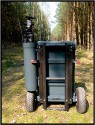 ZARGES TRANSPORTWAGEN - SELBSTBAU\n\nFoto und Text von Thomas Bder - VIELEN DANK!\n\nKommentar:\n\nTransport der Fotoausrstung\n\n \n\nNun ist es endlich soweit.\n\nLange habe ich an diesem Transportwagen geplant und gebaut.\n\nAuch wenn es vielleicht nicht so aussieht :-)\n\nBasis des Ganzen ist eine 60l Zarges Aluminiumkiste von der Bundeswehr.\n\nQuasi unkaputtbar und absolut wasserdicht.\n\nDie rckseitige Konstruktion besteht aus Aluminium und Eschenholz.\n\nHolz deshalb, weil es schn warm ist im Winter, man keine Schweihnde bekommt und Schlge gut abfedert werden.\n\nDie Eschenprofile sind als Nut und Feder ausgefhrt, damit man den Transportgriff ausziehen kann.\n\nIn die inneren Profile sind gefederte Bolzen eingebaut, die durch einen kleinen Seilzug nach innen gezogen werden knnen.\n\nDamit wird der Teleskopgriff entriegelt.\n\nDie weien Punkte an den Profilen, markieren die Einrastpositionen.\n\nUnten ist die Parkposition.\n\nNach oben hin gibt es Endanschlge aus Alu und Hartgummi, falls die Bolzen mal versagen sollten.\n\nDie luftgefllten Rder laufen auf einer 20mm Stahlrohrachse.\n\nDas blaue Beinchen unten, ist abschraubbar und nur fr den aufrechten Stand notwendig.\n\nBlau deshalb, um es im Ernstfall im Wald wiederzufinden ;-)\n\nAn einer Seite befindet sich die Halterung fr das Stativ.\n\nDieses Rohr hat unten ein eingeflochtenes Nylongarnnetz um das Stativ abzufedern und auch Wasser durchlaufen zu lassen.\n\nDie Stativhalterung ist innerhalb von Sekunden komplett abnehmbar, falls man kein Dreibein bentigt.\n\nDie beiden grauen Winkel mit den roten Kappen sind die Beine fr die liegende Position.\n\nIn der Box selbst gibt es zwei verstellbare Alutrennwnde.\n\nLinks und rechts befindet sich jeweils ein Einsatz einer Lowepro Stealth Reporter 500 AW Tasche.\n\nDiese 500er Taschen benutze ich normalerweise und kann somit wunderbar hin und her tauschen.\n\nIn der Mitte stehen einfach vier groe Objektivbecher nebeneinander.\n\nPlatz ist also mehr als genug...\n\nNun noch ein paar Daten:\n\nZum Zerlegen braucht man einen 4er und einen 6er Inbusschlssel, einen 13er Maulschlssel und einen normalen Kreuzschlitzschraubendreher.\n\nGewicht ca. 14kg also so ungefhr auf Pelicase Niveau nur mit dickeren Reifen :-)\n\nMae:\n\n60cm breit, 36cm tief, 73cm hoch (ohne Griff), mit ausgezogenem Griff 122cm\n\nInnenmae der Kiste:\n\n56cm breit, 37cm tief, 22cm hoch\n\nLink:\nhttp://www.makrofotografie.eu/index.php?option=com_content&view=article&id=47&Itemid=54