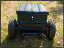 ZARGES TRANSPORTWAGEN - SELBSTBAU\n\nFoto und Text von Thomas Bder - VIELEN DANK!\n\nKommentar:\n\nTransport der Fotoausrstung\n\n \n\nNun ist es endlich soweit.\n\nLange habe ich an diesem Transportwagen geplant und gebaut.\n\nAuch wenn es vielleicht nicht so aussieht :-)\n\nBasis des Ganzen ist eine 60l Zarges Aluminiumkiste von der Bundeswehr.\n\nQuasi unkaputtbar und absolut wasserdicht.\n\nDie rckseitige Konstruktion besteht aus Aluminium und Eschenholz.\n\nHolz deshalb, weil es schn warm ist im Winter, man keine Schweihnde bekommt und Schlge gut abfedert werden.\n\nDie Eschenprofile sind als Nut und Feder ausgefhrt, damit man den Transportgriff ausziehen kann.\n\nIn die inneren Profile sind gefederte Bolzen eingebaut, die durch einen kleinen Seilzug nach innen gezogen werden knnen.\n\nDamit wird der Teleskopgriff entriegelt.\n\nDie weien Punkte an den Profilen, markieren die Einrastpositionen.\n\nUnten ist die Parkposition.\n\nNach oben hin gibt es Endanschlge aus Alu und Hartgummi, falls die Bolzen mal versagen sollten.\n\nDie luftgefllten Rder laufen auf einer 20mm Stahlrohrachse.\n\nDas blaue Beinchen unten, ist abschraubbar und nur fr den aufrechten Stand notwendig.\n\nBlau deshalb, um es im Ernstfall im Wald wiederzufinden ;-)\n\nAn einer Seite befindet sich die Halterung fr das Stativ.\n\nDieses Rohr hat unten ein eingeflochtenes Nylongarnnetz um das Stativ abzufedern und auch Wasser durchlaufen zu lassen.\n\nDie Stativhalterung ist innerhalb von Sekunden komplett abnehmbar, falls man kein Dreibein bentigt.\n\nDie beiden grauen Winkel mit den roten Kappen sind die Beine fr die liegende Position.\n\nIn der Box selbst gibt es zwei verstellbare Alutrennwnde.\n\nLinks und rechts befindet sich jeweils ein Einsatz einer Lowepro Stealth Reporter 500 AW Tasche.\n\nDiese 500er Taschen benutze ich normalerweise und kann somit wunderbar hin und her tauschen.\n\nIn der Mitte stehen einfach vier groe Objektivbecher nebeneinander.\n\nPlatz ist also mehr als genug...\n\nNun noch ein paar Daten:\n\nZum Zerlegen braucht man einen 4er und einen 6er Inbusschlssel, einen 13er Maulschlssel und einen normalen Kreuzschlitzschraubendreher.\n\nGewicht ca. 14kg also so ungefhr auf Pelicase Niveau nur mit dickeren Reifen :-)\n\nMae:\n\n60cm breit, 36cm tief, 73cm hoch (ohne Griff), mit ausgezogenem Griff 122cm\n\nInnenmae der Kiste:\n\n56cm breit, 37cm tief, 22cm hoch\n\nLink:\nhttp://www.makrofotografie.eu/index.php?option=com_content&view=article&id=47&Itemid=54