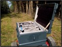 ZARGES TRANSPORTWAGEN - SELBSTBAU\n\nFoto und Text von Thomas Bder - VIELEN DANK!\n\nKommentar:\n\nTransport der Fotoausrstung\n\n \n\nNun ist es endlich soweit.\n\nLange habe ich an diesem Transportwagen geplant und gebaut.\n\nAuch wenn es vielleicht nicht so aussieht :-)\n\nBasis des Ganzen ist eine 60l Zarges Aluminiumkiste von der Bundeswehr.\n\nQuasi unkaputtbar und absolut wasserdicht.\n\nDie rckseitige Konstruktion besteht aus Aluminium und Eschenholz.\n\nHolz deshalb, weil es schn warm ist im Winter, man keine Schweihnde bekommt und Schlge gut abfedert werden.\n\nDie Eschenprofile sind als Nut und Feder ausgefhrt, damit man den Transportgriff ausziehen kann.\n\nIn die inneren Profile sind gefederte Bolzen eingebaut, die durch einen kleinen Seilzug nach innen gezogen werden knnen.\n\nDamit wird der Teleskopgriff entriegelt.\n\nDie weien Punkte an den Profilen, markieren die Einrastpositionen.\n\nUnten ist die Parkposition.\n\nNach oben hin gibt es Endanschlge aus Alu und Hartgummi, falls die Bolzen mal versagen sollten.\n\nDie luftgefllten Rder laufen auf einer 20mm Stahlrohrachse.\n\nDas blaue Beinchen unten, ist abschraubbar und nur fr den aufrechten Stand notwendig.\n\nBlau deshalb, um es im Ernstfall im Wald wiederzufinden ;-)\n\nAn einer Seite befindet sich die Halterung fr das Stativ.\n\nDieses Rohr hat unten ein eingeflochtenes Nylongarnnetz um das Stativ abzufedern und auch Wasser durchlaufen zu lassen.\n\nDie Stativhalterung ist innerhalb von Sekunden komplett abnehmbar, falls man kein Dreibein bentigt.\n\nDie beiden grauen Winkel mit den roten Kappen sind die Beine fr die liegende Position.\n\nIn der Box selbst gibt es zwei verstellbare Alutrennwnde.\n\nLinks und rechts befindet sich jeweils ein Einsatz einer Lowepro Stealth Reporter 500 AW Tasche.\n\nDiese 500er Taschen benutze ich normalerweise und kann somit wunderbar hin und her tauschen.\n\nIn der Mitte stehen einfach vier groe Objektivbecher nebeneinander.\n\nPlatz ist also mehr als genug...\n\nNun noch ein paar Daten:\n\nZum Zerlegen braucht man einen 4er und einen 6er Inbusschlssel, einen 13er Maulschlssel und einen normalen Kreuzschlitzschraubendreher.\n\nGewicht ca. 14kg also so ungefhr auf Pelicase Niveau nur mit dickeren Reifen :-)\n\nMae:\n\n60cm breit, 36cm tief, 73cm hoch (ohne Griff), mit ausgezogenem Griff 122cm\n\nInnenmae der Kiste:\n\n56cm breit, 37cm tief, 22cm hoch\n\nLink:\nhttp://www.makrofotografie.eu/index.php?option=com_content&view=article&id=47&Itemid=54